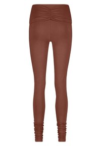 Leggings ajustés de couleur rouille avec une large taille froncée et un détail froncé au niveau des chevilles. Fabriqués dans un tissu lisse et extensible.