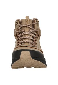 Beige vandringskänga med texturerat tygövre, bruna accenter och tjock svart gummisula. Har framträdande snören och förstärkta hål.