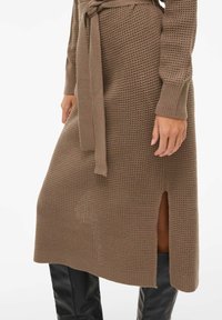 Sukienka swetrowa w kolorze taupe, z fakturowanym splotem, długimi rękawami, rozcięciem po boku oraz pasem z tkaniny w talii.