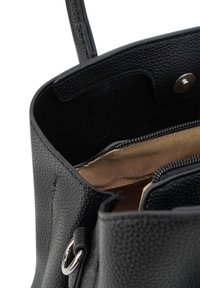Zwart leren handtas met een gestructureerd oppervlak, voorzien van een ritsvak en een gouden stoffen voering aan de binnenkant. Inclusief zilveren hardware accenten.