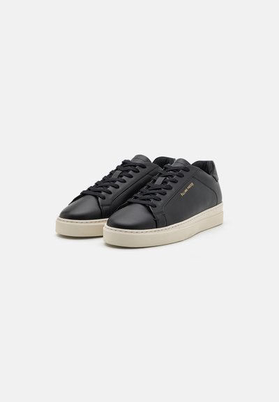 Sorte lær-sneakers med en glat tekstur, hvide gummisåler og sorte snørebånd. Med diskret guldbranding på siden.