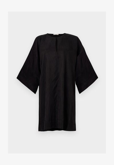 Svart tunika i stil av mjukt material, med rund hals, korta vida ärmar och en central slitsdetalj. Enkel och avkopplad passform.