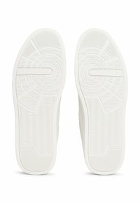 Suelas de zapatillas blancas con patrones texturizados, que presentan elementos de diseño en espiga y circulares, con la marca "TOMMY HILFIGER".