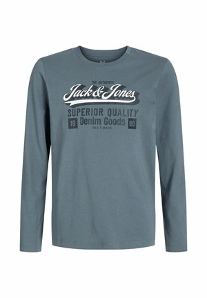 Garās piedurknes krekls pelēkzili tonī. Uz tā ir teksts "Jack & Jones" un "Superior Quality Denim Goods" kontrastējošās baltā un tumši pelēkā krāsā.