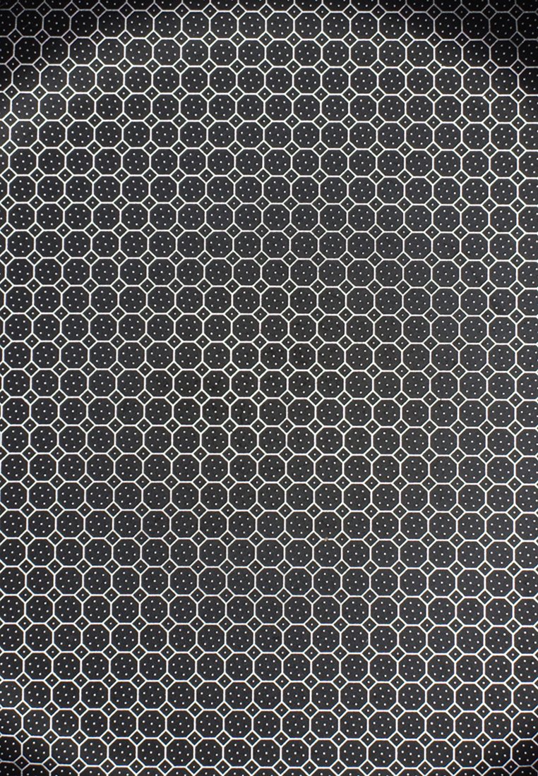 Černý povrch s opakujícím se vzorem bílých hexagonů a teček. Materiál vypadá hladce s matným povrchem.