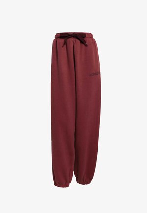 Pantalons de survêtement bordeaux avec taille élastique et cordon de serrage. Chevilles côtelées et marquage minimal sur la jambe gauche. Texture de tissu douce et lisse.