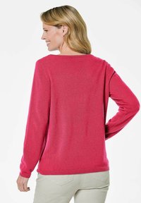 Fuchsia trui met lange mouwen, ronde halslijn en een zachte textuur. Heeft ribbels aan de mouwen en de zoom, geschikt voor casual draagstijl.