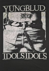 �Černé tričko s grafickým potiskem, na němž je pásek, řetěz a roztrhané džíny. Text zní "YUNGBLUD IDOLS IDOLS" tučným bílým písmem.