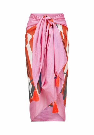 Longue jupe portefeuille rose avec un grand nœud sur le devant et des pampilles orange, présentant des motifs géométriques orange, blancs et noirs audacieux en dessous.