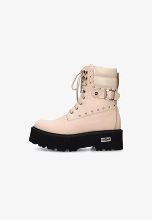 Stivale alla caviglia beige con lacci, suola piattaforma nera chunky, rivetti metallici, colletto imbottito, fibbia laterale e logo del marchio sul tallone.