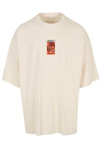 Krem oversized t-skjorte, rund hals, med et fargerikt grafisk stoffmerke med "PEACE" og "NO WAR." Myk tekstil, avslappet passform, korte ermer.