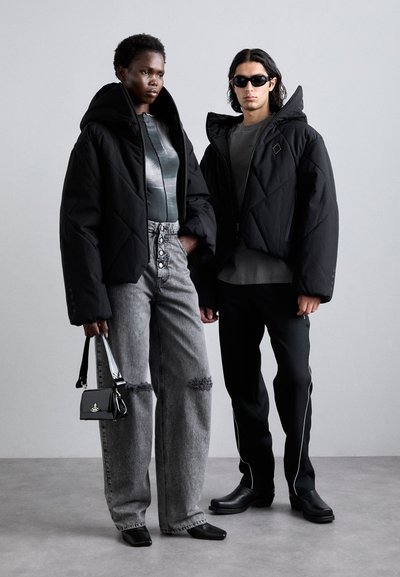 Doudounes noires avec capuches, body graphique gris, jeans déchirés taille haute, lunettes de soleil noires et un petit sac à main noir.