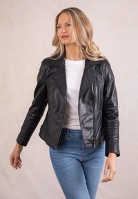 Black leather motorcycle jacket with a zip closure, lapel collar, and ribbed accents on the sleeves. Worn over a white shirt and blue jeans.