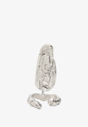 Abstrakcyjny srebrny pierścień zaprojektowany, aby przypominał teksturowany kamień, z otwartą obrączką i szczegółowymi akcentami przypominającymi małe pazury u podstawy.