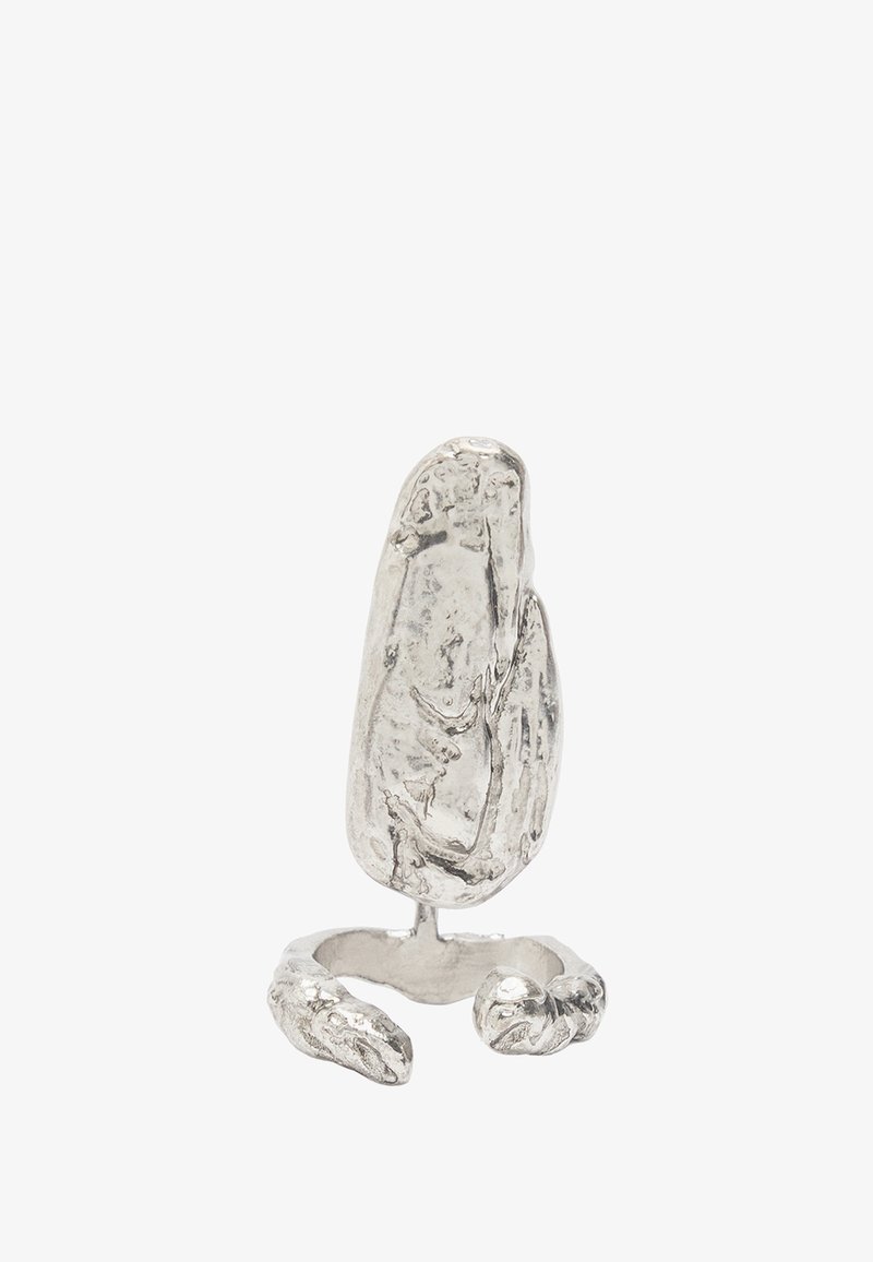 Abstrakcyjny srebrny pierścień zaprojektowany, aby przypominał teksturowany kamień, z otwartą obrączką i szczegółowymi akcentami przypominającymi małe pazury u podstawy.