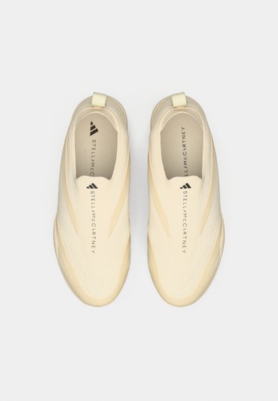 Par van beige instappers met een textuur op de bovenkant en "Stella McCartney" gedrukt op het middelste deel van elke schoen.
