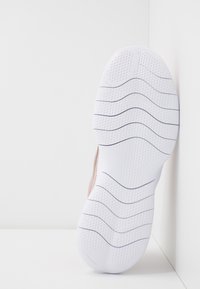 Semelle de basket en caoutchouc blanc avec motifs de grip texturés, présentant un accent rose sur le bord supérieur. Fini lisse avec des rainures de flexion.