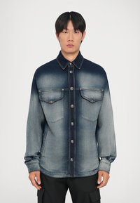 Jeans μπουφάν με ξεθωριασμένο gradient από σκούρο μπλε στην κορυφή μέχρι ανοιχτό μπλε στο κάτω μέρος, με δύο τσέπες στο στήθος και ασημένια κουμπιά.
