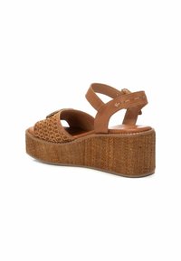 Sandalias de plataforma marrones con parte superior de tejido trenzado, correas anchas y un tacón texturizado similar al corcho. Diseño de punta abierta y correa en el tobillo.