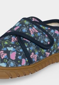 Chausson enfant avec base bleue, imprimé papillons rose et jaune, bride Velcro réglable et semelle en caoutchouc marron.
