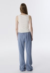 Crème tanktop gecombineerd met lichtblauwe, losse broek met decoratieve rhinestones langs de zijnaad. Soepele textuur, casual ontwerp.