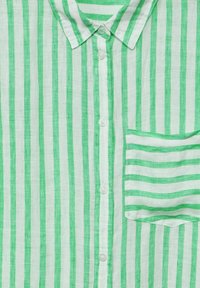 Green and white striped shirt made of lightweight fabric. Features a button front, collar, and a patch pocket with horizontal stripes.