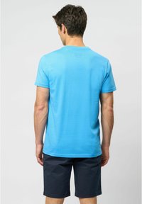 Herreblå T-shirt med korte ærmer og rund hals, lavet af letvægtsstof. Båret med marineblå shorts, minimal logodetalje på bagsiden.