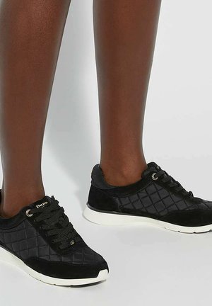 Zwarte gewatteerde sneakers met een combinatie van stof en suede, voorzien van ronde veters en witte rubberen zolen. Gouden accenten aan de zijkant.