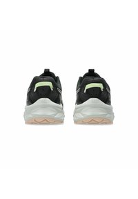 Par de zapatillas de correr negras con mediasolados blancos y suelas beige, vistas desde atrás sobre un fondo blanco.