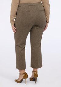 Brązowe spodnie w kratę houndstooth o prostym kroju, z dwiema tylnymi kieszeniami i elastycznym pasaem. W połączeniu z błyszczącymi brązowymi szpilkami.