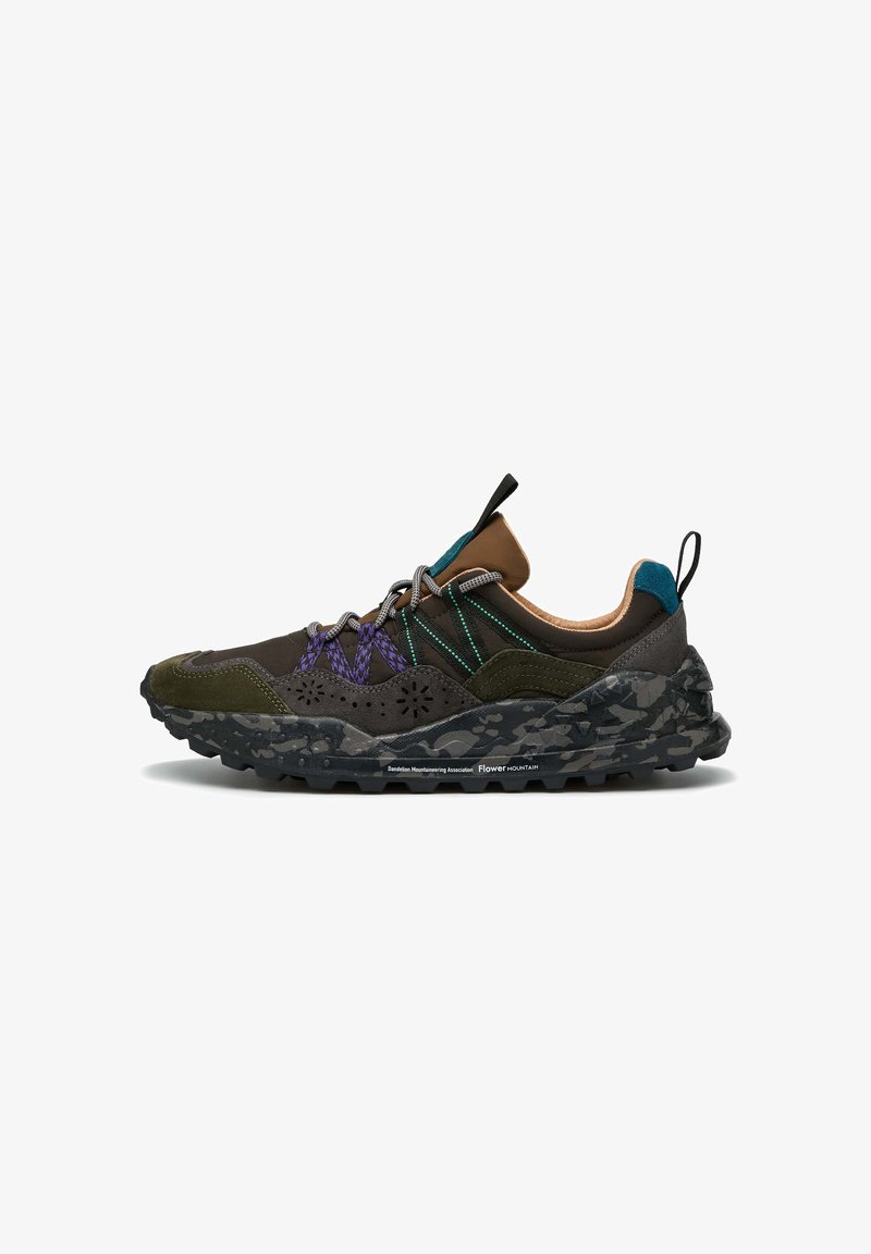 Chaussure de randonnée multicolore avec une tige verte et marron, des accents en mesh, des lacets violets et turquoise, et une semelle en camouflage noir texturé.