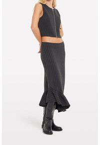 Černobíle pruhovaný dvoudílný set obsahující bezramínkový cropped top se zipem a dlouhou sukni s volánkovým lemem.