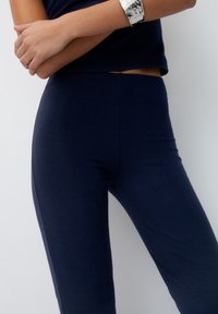 Námořnické modré žebrované legíny s přiléhavým střihem, které mají hladký povrch a vysoký pas. Bez viditelných švů nebo ozdob.