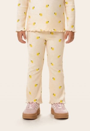 Copil purtând pantaloni și top crem cu textura nervurată și imprimeuri galbene cu lămâi, asortați cu adidași cu platformă roz.