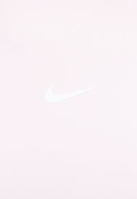 Jasnoróżowa koszulka Nike o miękkiej fakturze, z wyraźnym białym logo. Prosty design bez wzorów ani dodatkowych akcentów.