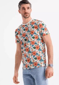 Korte mouwen bloemen t-shirt met een witte achtergrond, versierd met rode en oranje hibiscus bloemen en groene bladeren. Ronde halslijn, zachte stof.