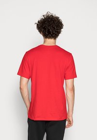 Red cotton T-shirt with short sleeves and a round neckline, featuring a plain design and regular fit, viewed from the back.