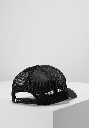 Casquette de baseball noire en mesh avec fermeture ajustable à pression, posée sur une surface blanche sur fond gris clair uni.