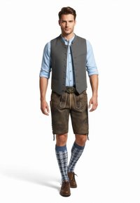 Gilet di lana grigio sopra una camicia azzurro chiaro, abbinato a pantaloni corti in pelle marrone. Calzettoni a righe blu e bianche fino al ginocchio e scarpe marroni.