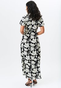 Black floral dress with short sleeves, featuring large white flower patterns and a floor-length design. Smooth fabric with a fitted silhouette.