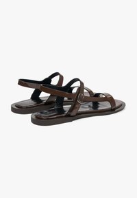 Bruine platte sandalen met glanzende banden, een gestructureerde voetbed en een minimalistisch ontwerp met een verstelbare enkelgesp en een gladde zool.