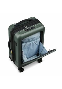 Valise rigide verte avec accents noirs, roues doubles et un compartiment intérieur à rayures bleues. Comprend une fermeture éclair et un cadenas à combinaison.