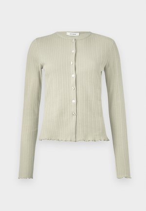 Lysegrønn ribbestrikket cardigan med lange ermer, rund hals og fem knapper foran. Har en bølgete skjæring og myk tekstur.
