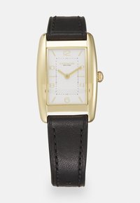 Montre rectangulaire dorée avec un cadran blanc, un bracelet en cuir noir, des index en or et une petite couronne accentuée.