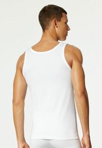 White cotton tank top featuring a rounded neckline, narrow shoulder straps, and a fitted design, showing the back and shoulders.