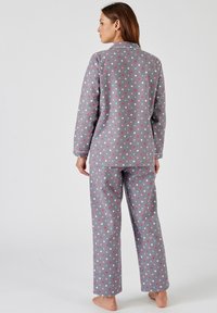 Grijze pyjama set met een knoopsluiting aan de bovenkant en broek, versierd met veelkleurige stippen in roze, blauw en wit, gemaakt van zacht stof.