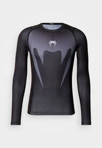 Długi rękaw koszulki sportowej w czerni i szarości, z teksturowanym wzorem, wyraźnym logo na klatce piersiowej oraz gładkim materiałem.