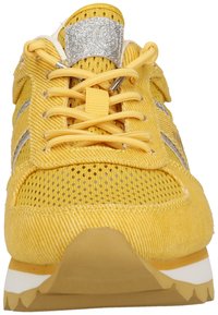 Yellow athletic shoe with mesh and textured fabric, silver accents, and a padded tongue. Features thick rubber sole with a zigzag pattern.