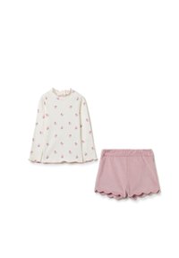 Langärmliges Oberteil in Creme mit pinkem Blumenmuster und Rüschensaum; kombiniert mit pinken Shorts mit gewelltem Saum. Glatte Textur, lässiges Design.