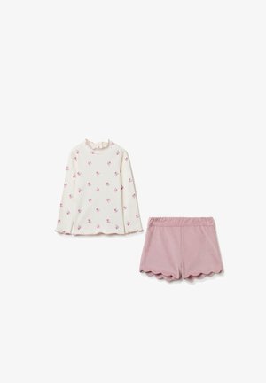 Blusa de manga larga en color crema con estampado floral rosa y cuello con volantes; combinada con shorts rosa con dobladillo ondulado. Textura suave, diseño casual.